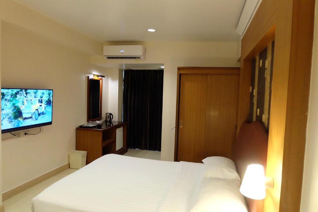 - une chambre avec un lit blanc et une télévision à écran plat dans l'établissement Synsiri Lat Phrao 83, à Ban Zong Katiam