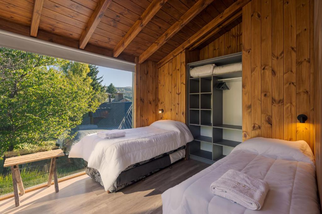 two beds in a room with a large window at Complejo Playa Bonita in San Martín de los Andes