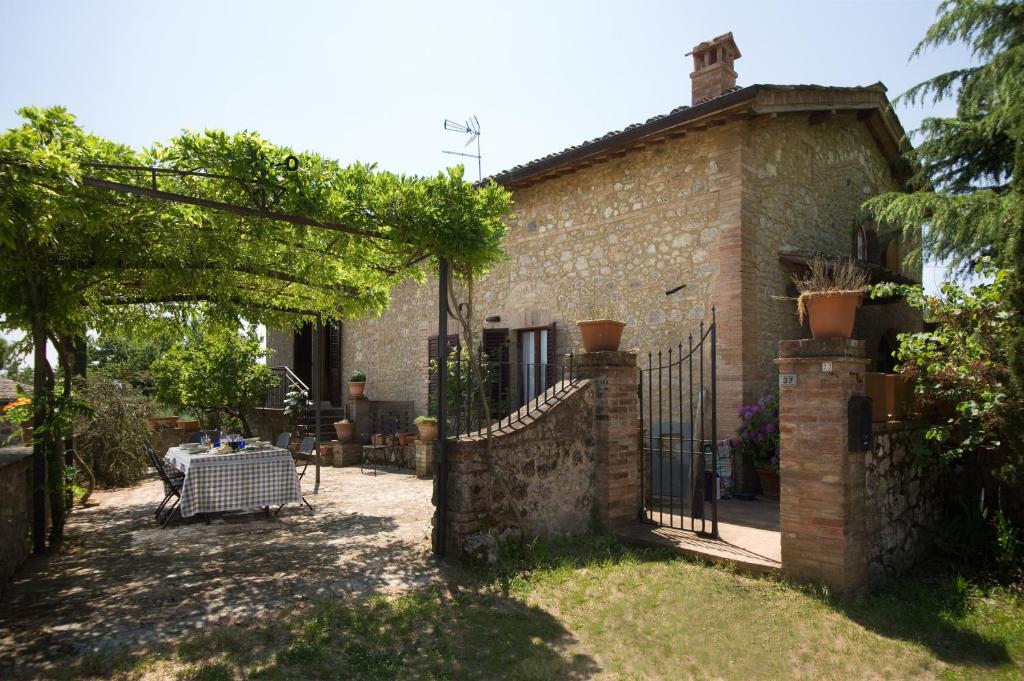 une maison en briques avec un portail et une table dans la cour dans l'établissement Agriturismo San Giusto, à Sovicille