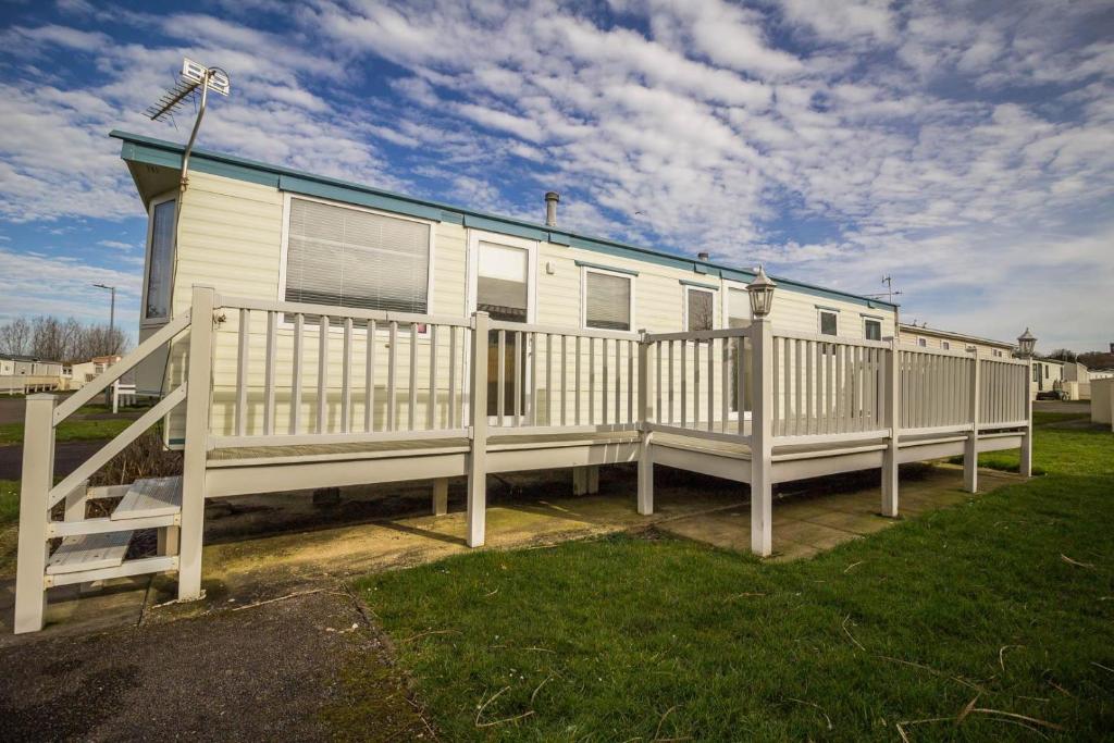 a mobile home with a porch and a fence at Caravan With Decking At Manor Park, Nearby Hunstanton Beach Ref 23013c in Hunstanton