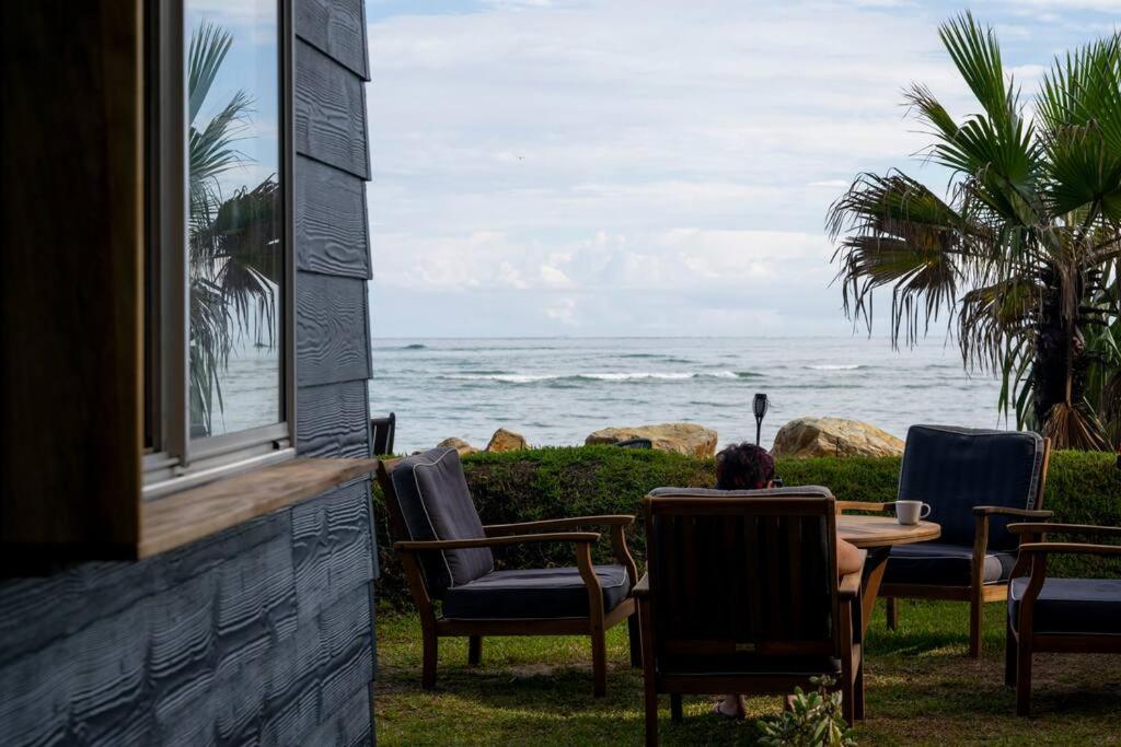 una persona sentada en una mesa mirando al océano en Norm's Place + Waterfront House + Beachfront, en Amity Point