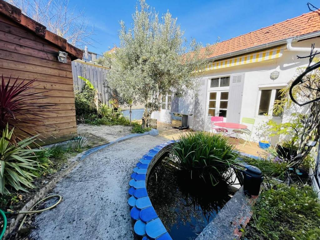 une cour arrière avec un jardin avec une jardinière bleue dans l'établissement Maison Arcachon: proche centre, plage et parc. Terrasse ensoleillée, 2 mezzanines, animaux acceptés. - FR-1-433-101, à Arcachon