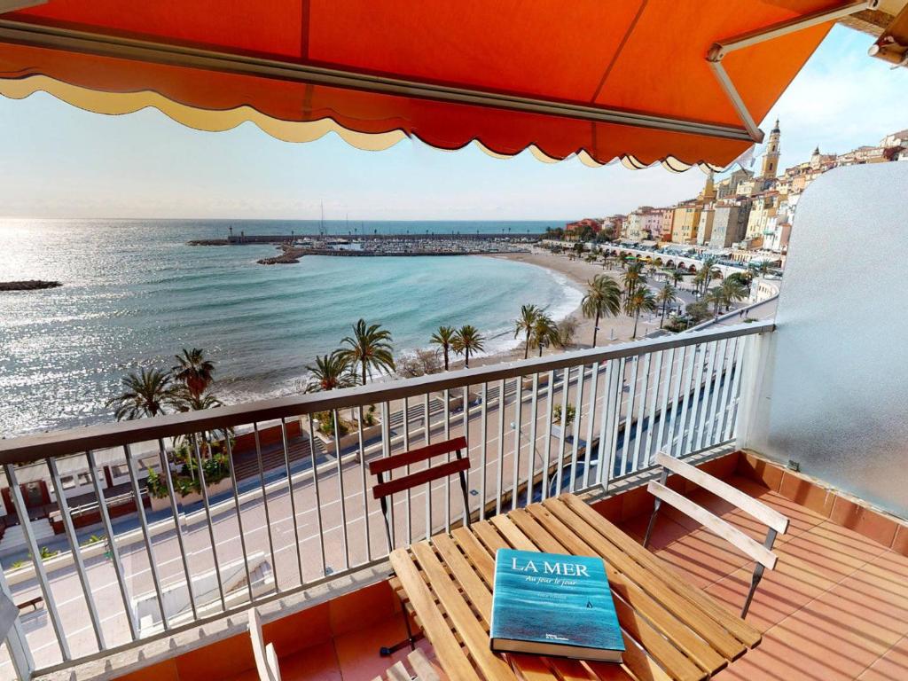 d'un balcon avec une table et une vue sur la plage. dans l'établissement Appartement spacieux avec terrasse face mer à Menton, proche plages et centre-ville - FR-1-196-327, à Menton