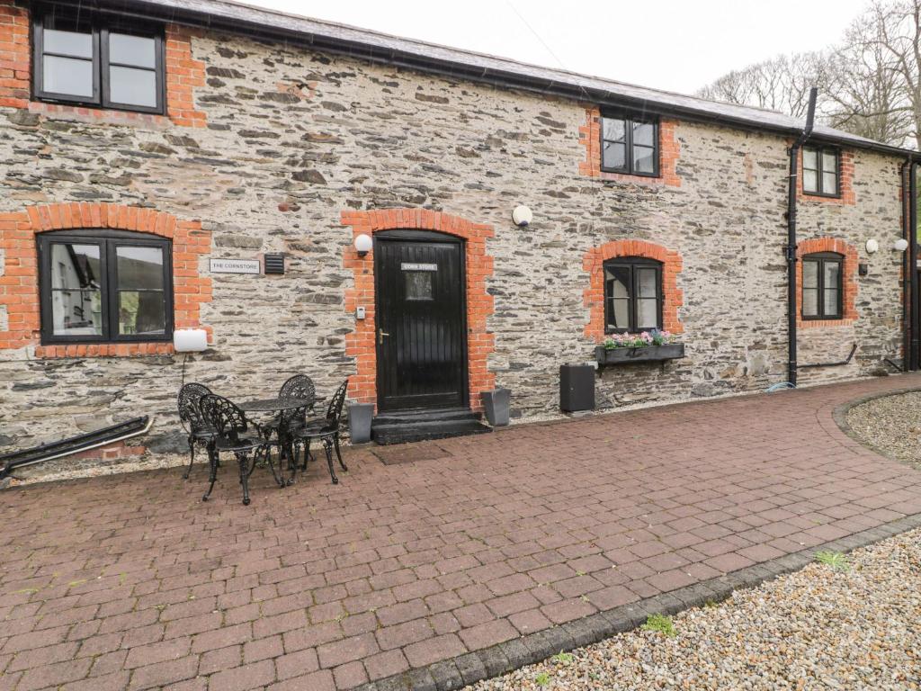due tavoli e sedie di fronte a un edificio di mattoni di The Corn Store a Corwen