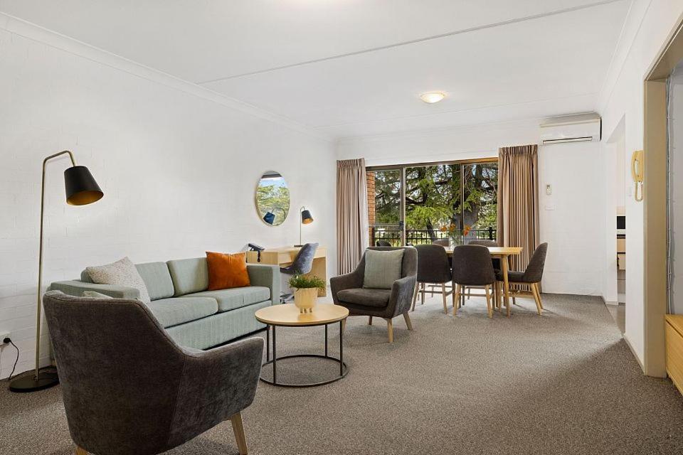 sala de estar con sofá, sillas y mesa en Oxley Court Serviced Apartments en Canberra