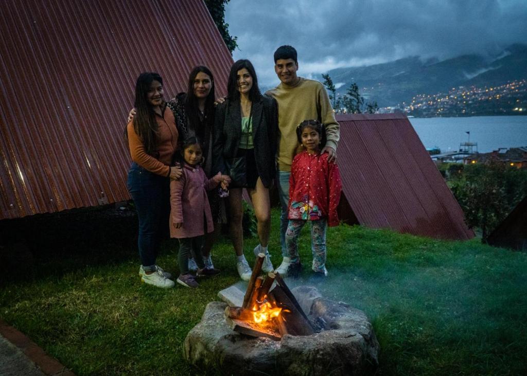 una familia de pie junto a una hoguera en Glamping Campo Lago San Pablo, en Otavalo