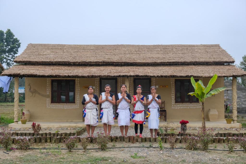 un grupo de chicas delante de una casa en Tharu Community Lodge en Kawasoti