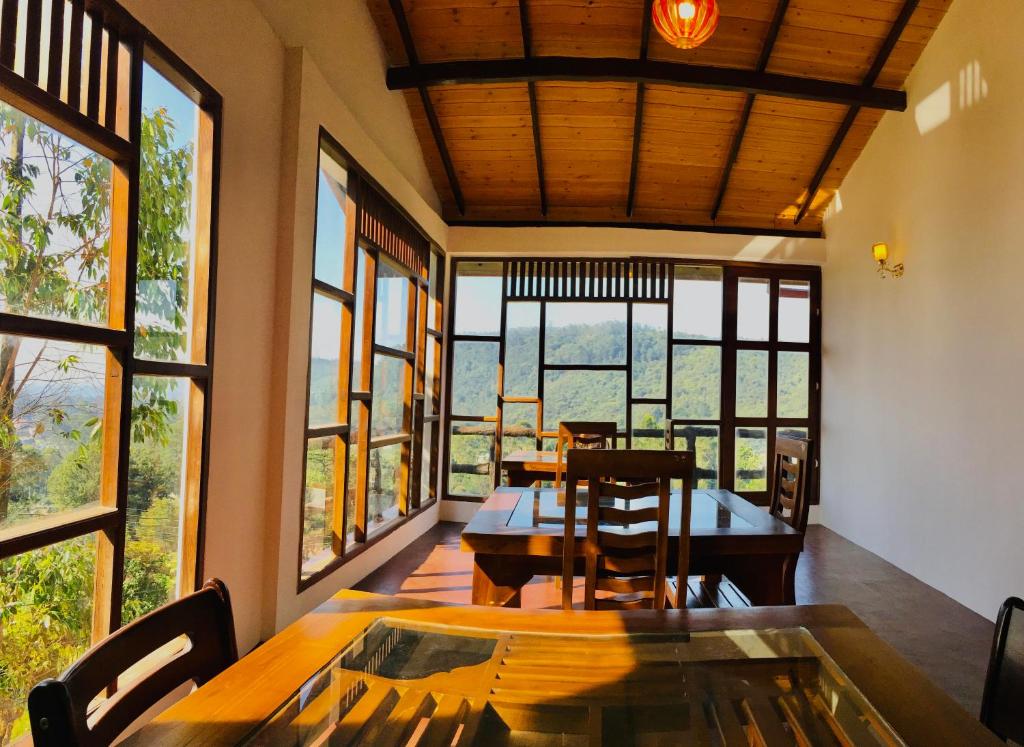 uma sala de jantar com mesas, cadeiras e janelas em travellers nest inn em Nuwara Eliya