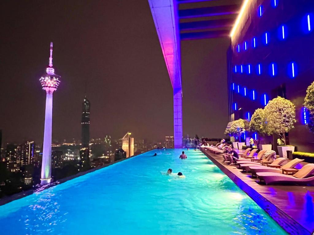 una piscina con gente en la ciudad por la noche en The Platinum KLCC By Sky Pool, en Kuala Lumpur