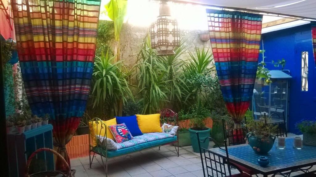 un patio con cortinas coloridas y un sofá en Chez Janine, en Saint-Laurent-dʼAigouze