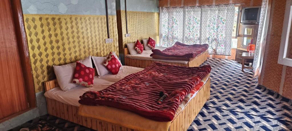 a room with three beds with red pillows on them at New Snow View Resort pahalgam in Pahalgām
