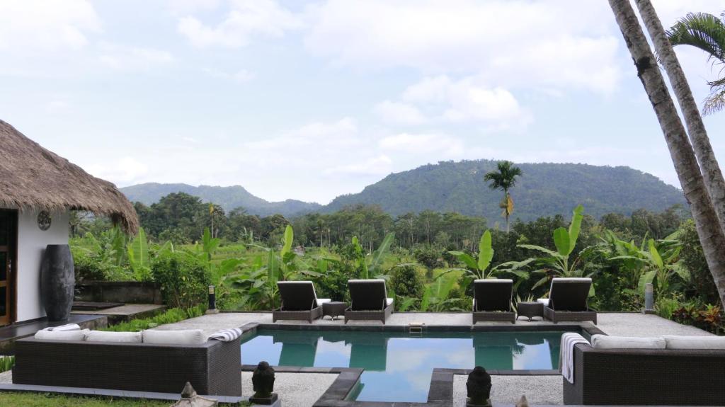 a resort pool with chairs and mountains in the background at VILLA BAMBOO in Silebeng