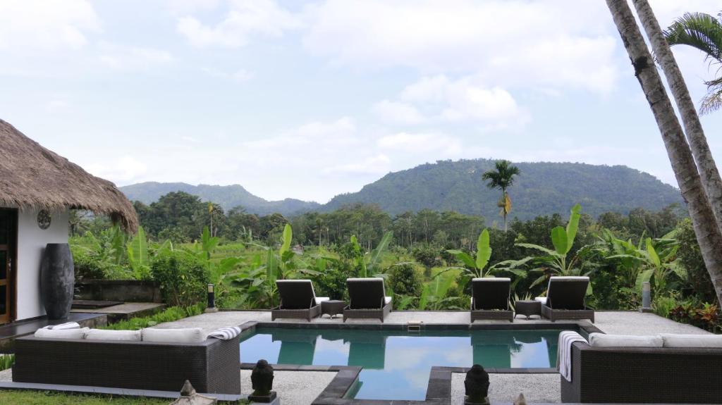 a resort pool with chairs and mountains in the background at The Kubu Authentic Quite Place with Nice View in Silebeng