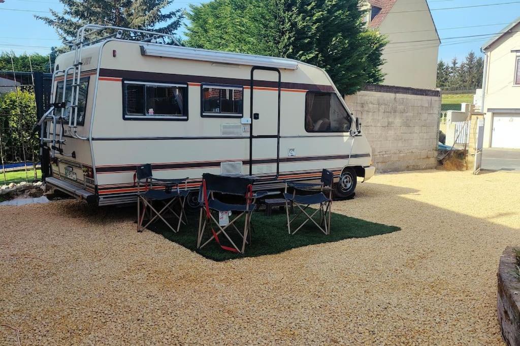 ein weißer Wohnwagen in einem Hof mit einem Tisch und Stühlen in der Unterkunft Camping-car vintage in Venette