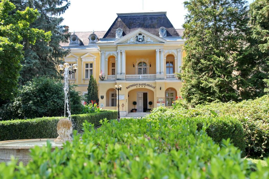 una casa amarilla con una fuente frente a ella en Batthyány Kastélyszálló en Zalacsány