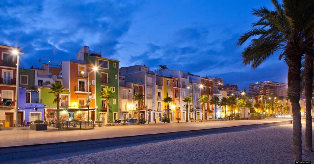 une rue de la ville de nuit avec des palmiers et des bâtiments dans l'établissement HAPPYVILA Apartments, à La Vila Joiosa