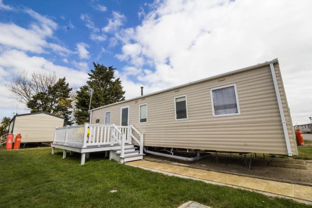 a mobile home with a porch and a deck at Great 8 Berth Caravan For Hire At Seawick Holiday Park In Essex Ref 27227sw in Clacton-on-Sea