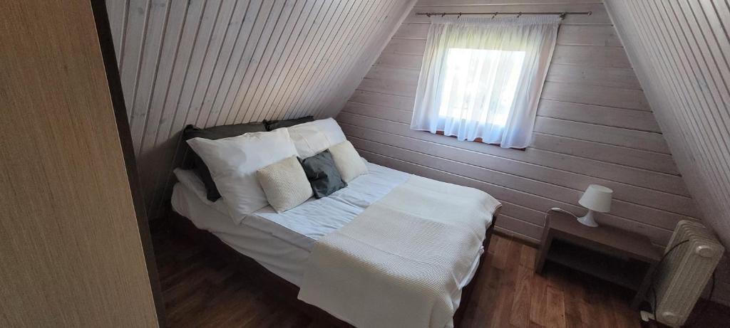 a small bed in a room with a window at Domki letniskowe Kika in Sarbinowo