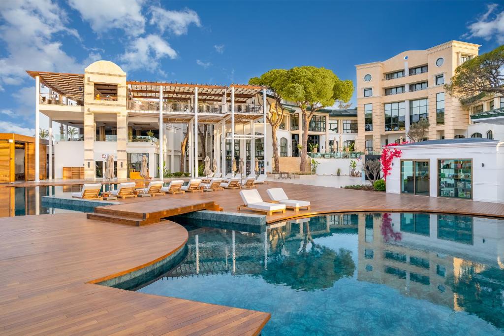 a swimming pool with chairs and a building at Rixos Park Belek - The Land Of Legends Access in Belek