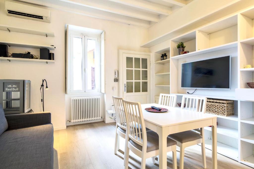 uma sala de estar com uma mesa e cadeiras e uma televisão em Lovely apartment on the Navigli river by Easylife em Milão
