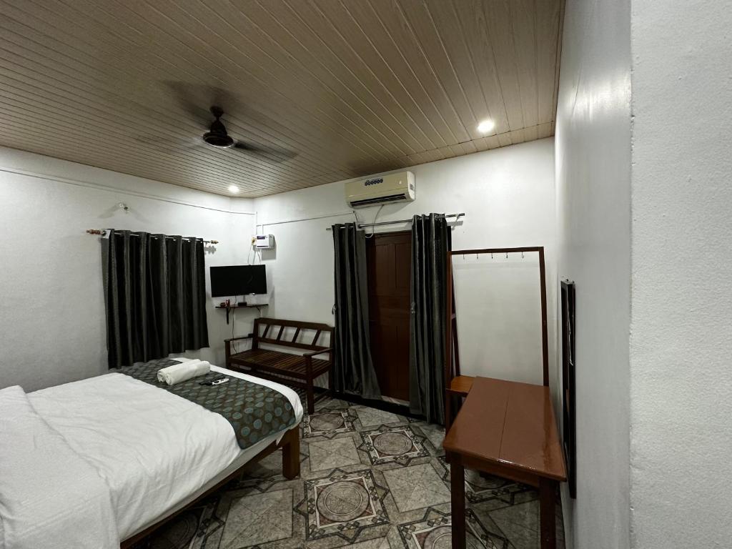 a bedroom with a bed and a desk and a table at Ocean Way Guest House in Baga