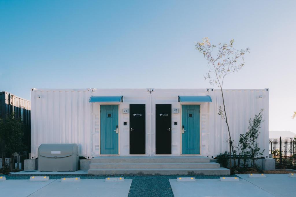 un edificio blanco con puertas azules y piscina en 天草VIVID V1, en Kami Amakusa