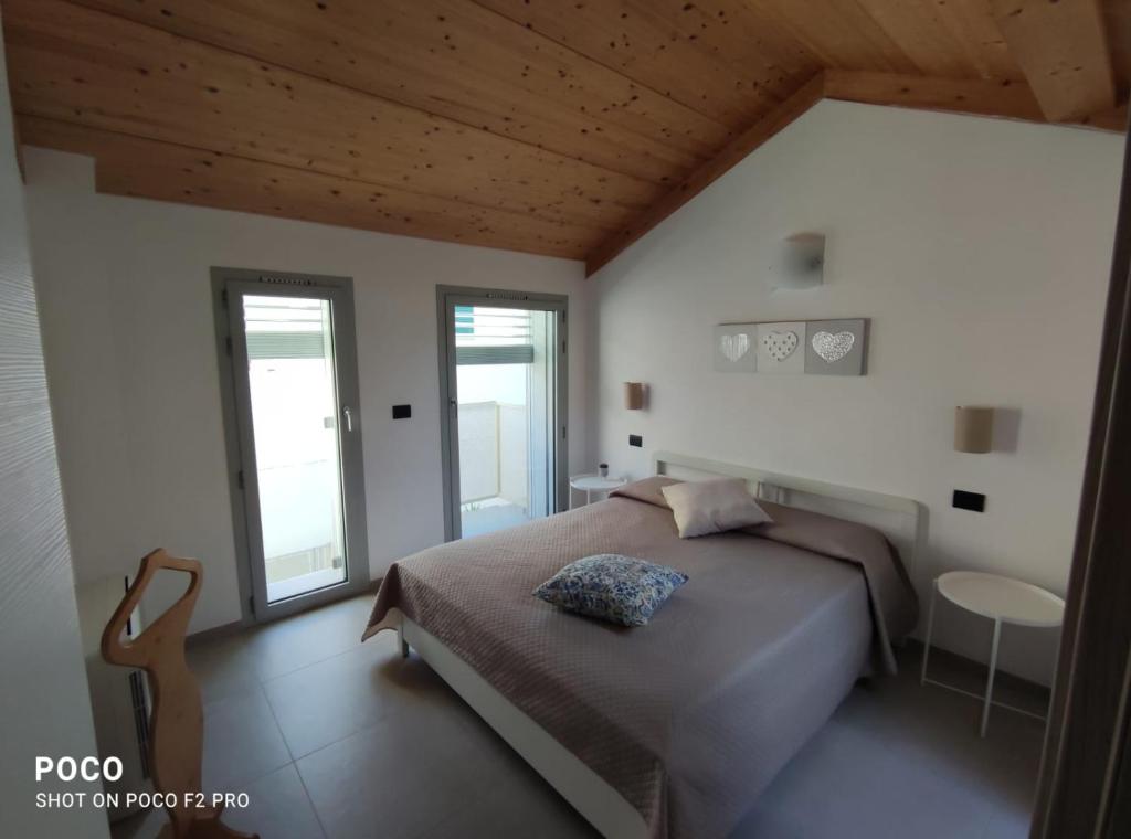 a bedroom with a large bed and two windows at Case Vacanze Paola in Santo Stefano al Mare
