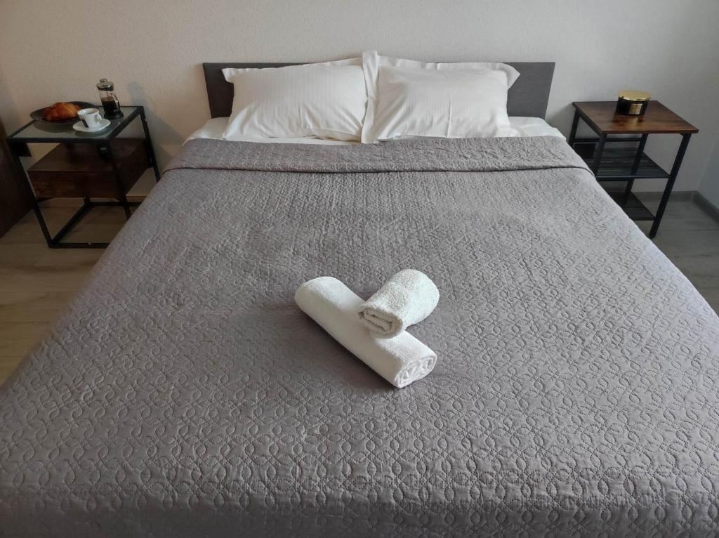 ein weißes Handtuch auf einem Bett mit zwei Tischen in der Unterkunft TROFFI T14- SELF CHECK-IN apartment for your comfort in Mažeikiai
