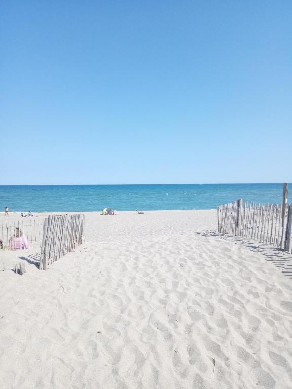 une plage avec une clôture dans le sable et l'océan dans l'établissement appartement 6p rez-de-jardin clim accés mer direct, au Barcarès