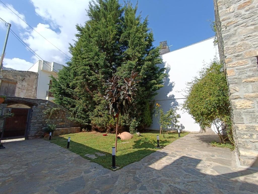 a tree in a yard next to a building at Casa di Pietra in Neápolis