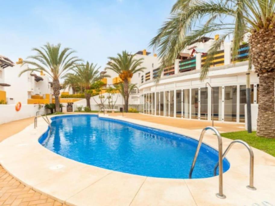 een zwembad voor een gebouw met palmbomen bij Lomas del Mar 5 Magnifique appart -piscine chauffée , paddle, clim, Vue panoramique in Playas de Vera