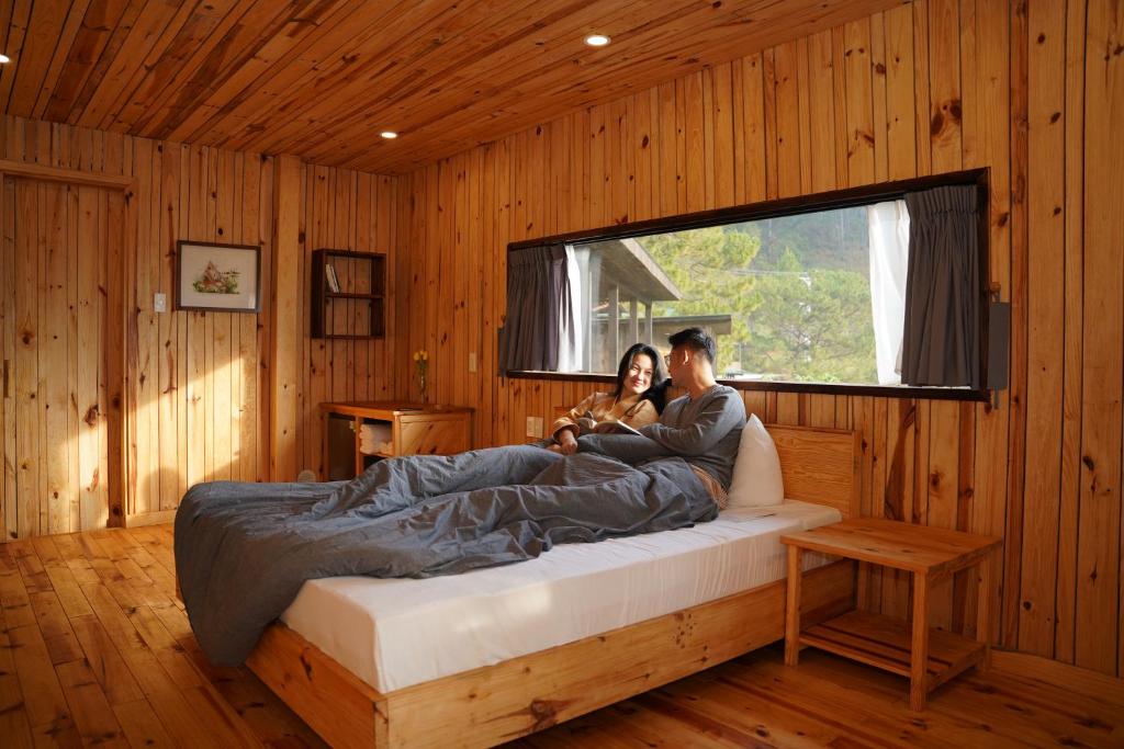 a man and a woman sitting on a bed in a room at Lavender Dalat Hotel and Resorts in Da Lat