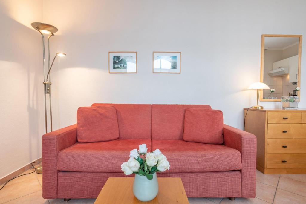 ein Wohnzimmer mit einem roten Sofa und einem Tisch mit Blumen in der Unterkunft Fewo 641, Seepark Sellin in Ostseebad Sellin