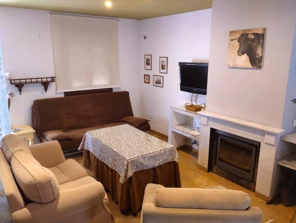 een woonkamer met een bank, een tafel en een televisie bij Casita de ensueño en Ronda in Ronda
