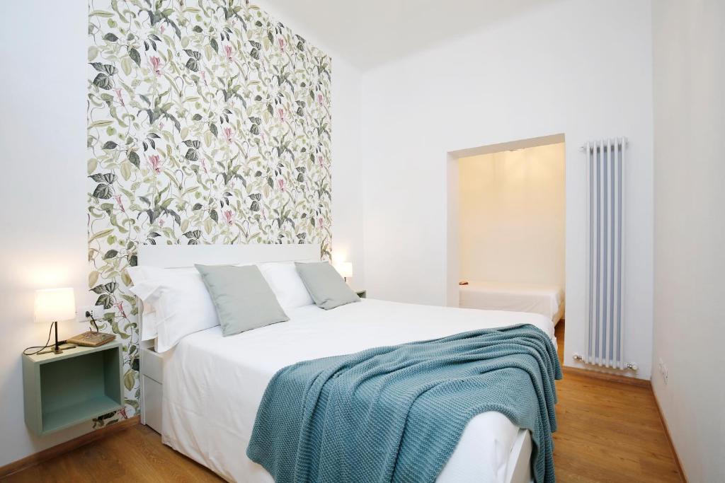 um quarto com uma grande cama branca e uma cabeceira floral em Appartamenti Diffusi di Villa Fiorita em Cattolica