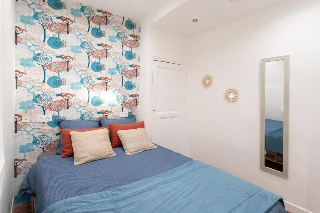 a bedroom with a blue bed with a floral wall at 26 nice in Nice