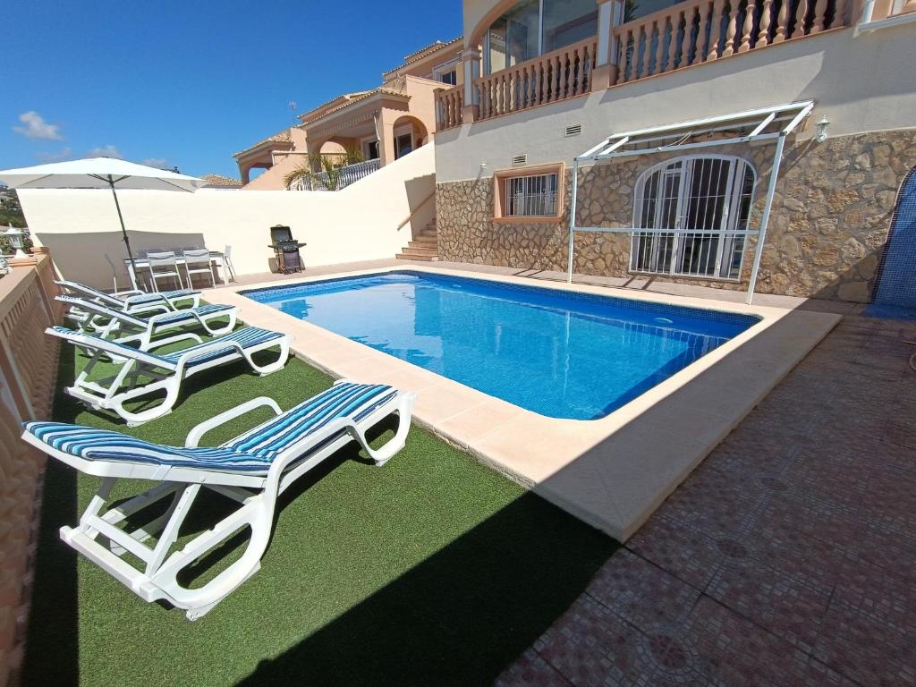- une piscine avec 2 chaises longues et une table dans l'établissement Villa Noemi, con piscina privada, à Calp