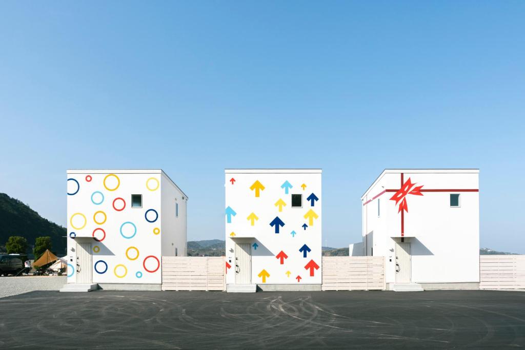 eine Gruppe von drei weißen Gebäuden mit farbenfroher in der Unterkunft 淡路島貸別荘リアンみなと in Minamiawaji