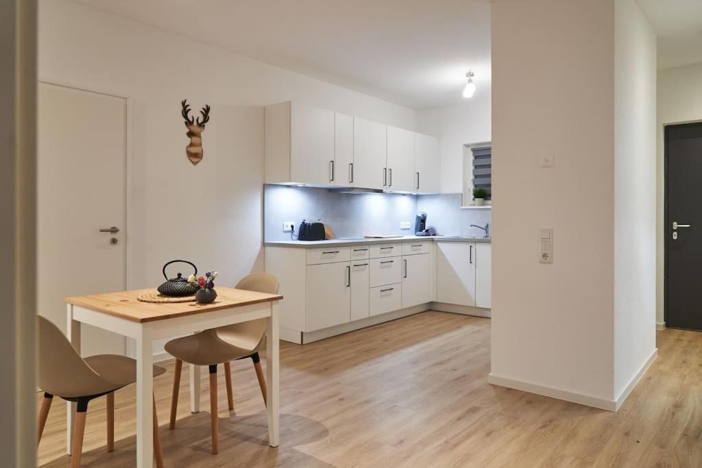 a kitchen with white cabinets and a table and chairs at Wohnen auf Zeit & Ferien in Wehr - Apartment Sand in Wehr
