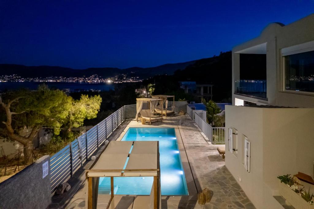 a villa with a swimming pool at night at Be Home Sea View in Porto Rafti