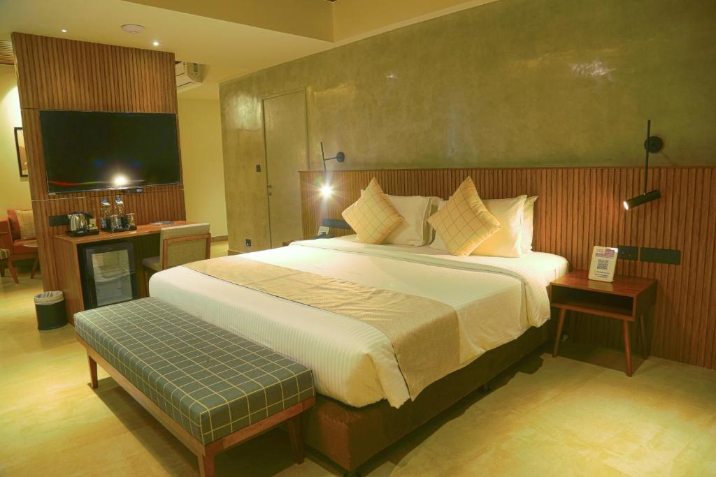 1 dormitorio con 1 cama grande y TV en GReaT trails yercaud by GRT Hotels, en Yercaud