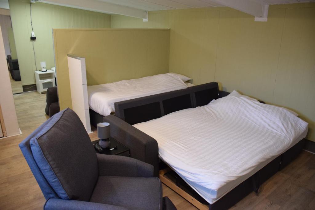 1 dormitorio con 1 cama, 1 silla y 1 sofá en camping family room, en Ter Aar