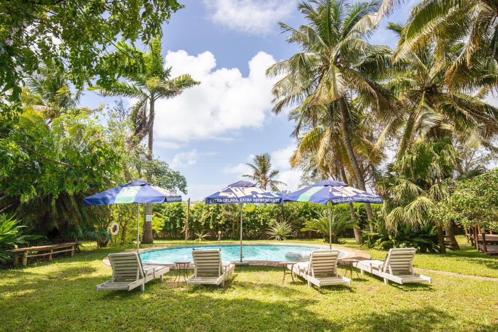 a swimming pool with chairs and umbrellas at LEMON BEACH LODGE Vilankulo in Vilanculos