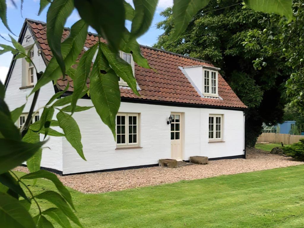 ein weißes Haus mit rotem Dach in der Unterkunft The Mansion Cottage in Tetford