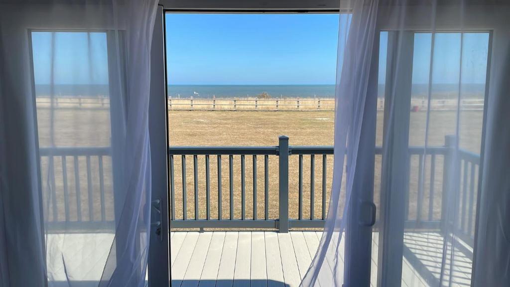 a balcony with a view of the beach from a window at Stunning Caravan With Full Sea Views At Broadland Sands In Suffolk Ref 20236bs in Hopton on Sea
