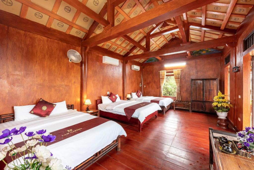 3 łóżka w pokoju z drewnianymi ścianami i drewnianą podłogą w obiekcie Tam Coc Sunshine Resort w mieście Ninh Binh