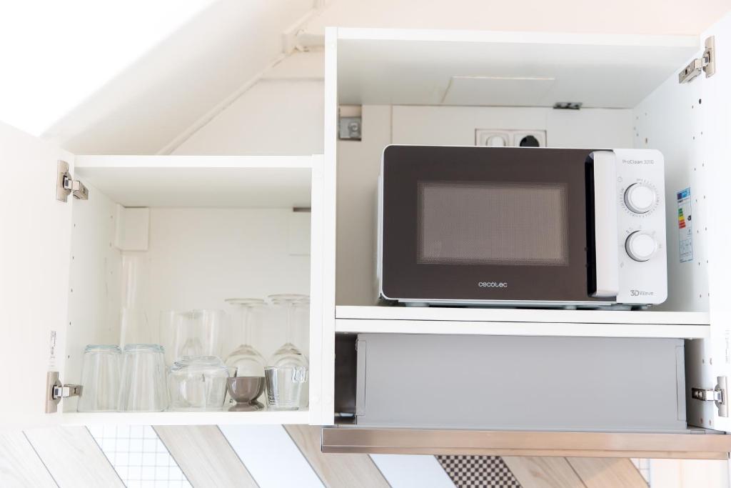 a microwave oven in a white cabinet in a kitchen at Auguste, La Romaine et My César - Location Saverne in Saverne
