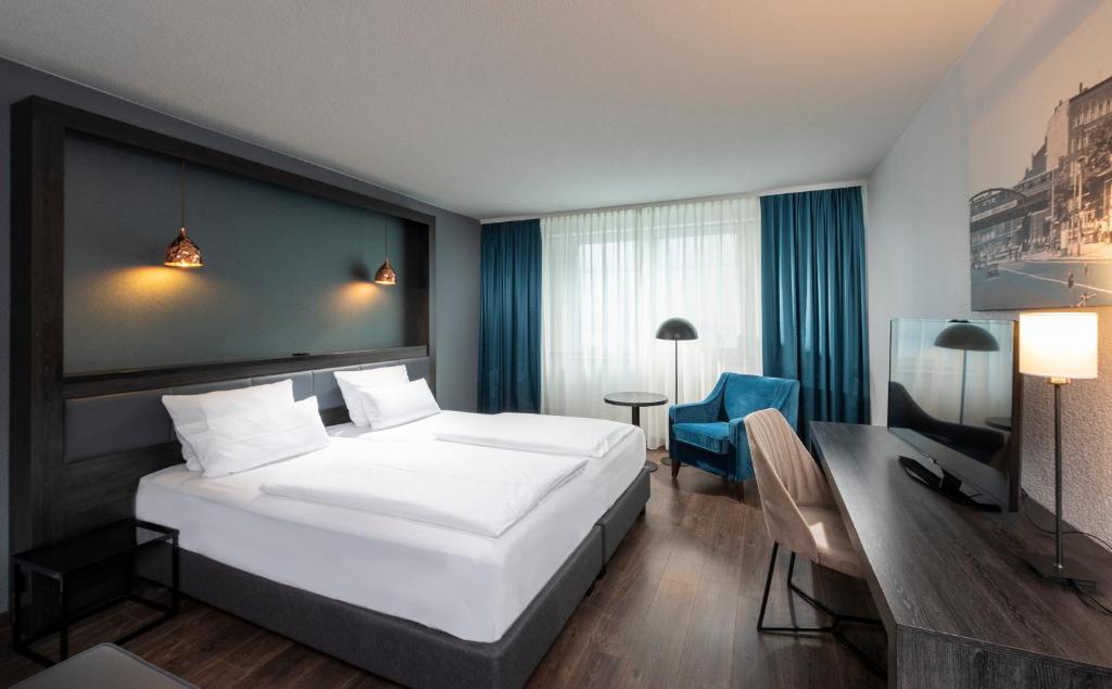 een slaapkamer met een groot wit bed en een bureau bij City Hotel Berlin East in Berlijn