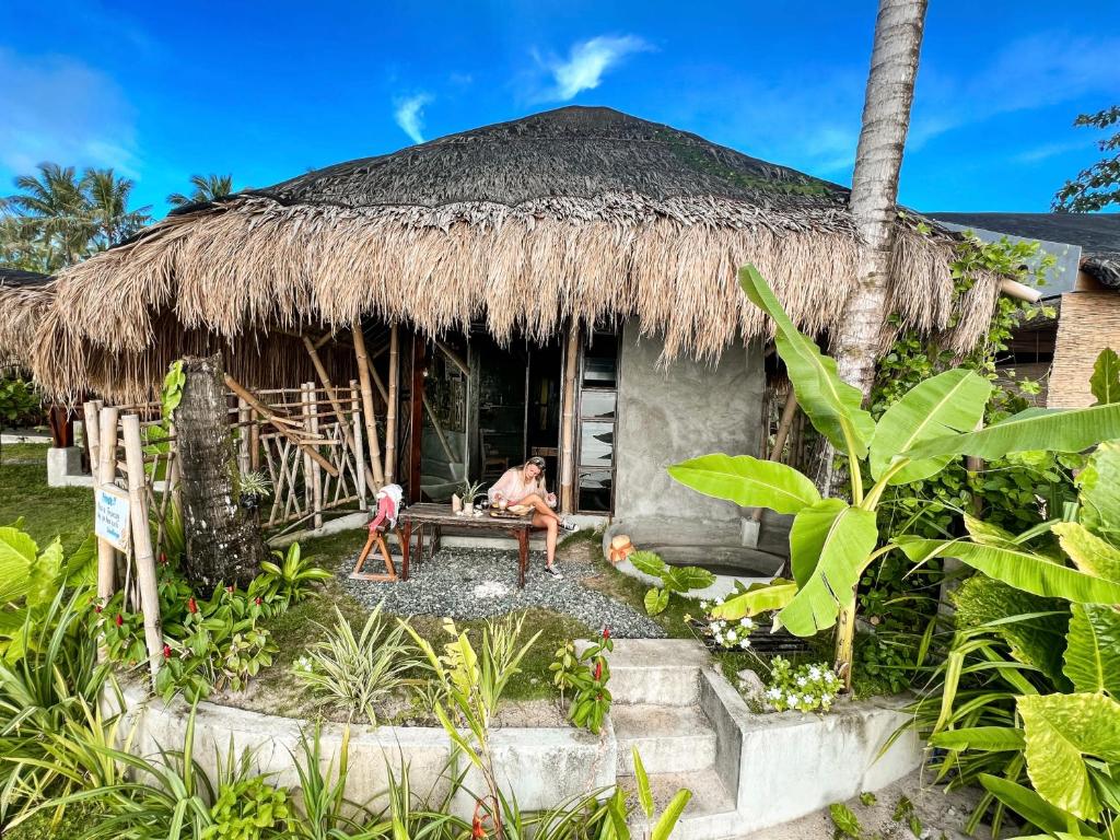 a man sitting on a bench outside of a hut at shakabrah beach club cottage in General Luna