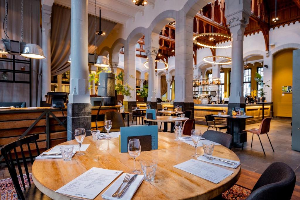 a dining room with a wooden table and chairs at Post-Plaza Hotel & Grand Café in Leeuwarden